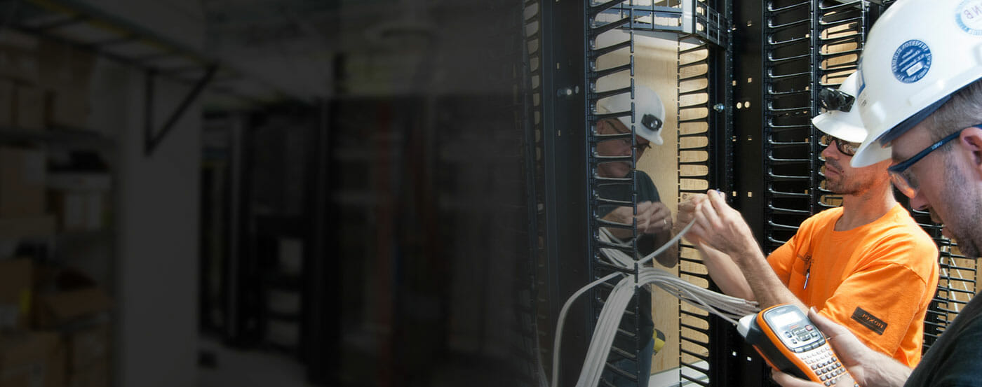 Photo of technicians working on an electrical rack