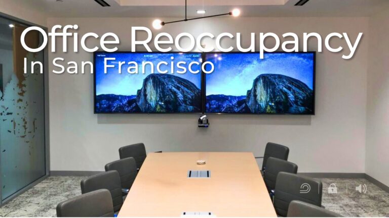 Conference room with a long meeting table and dual wall-mounted display screens used for video conferencing, representing modern office infrastructure supporting workplace reoccupancy in San Francisco.