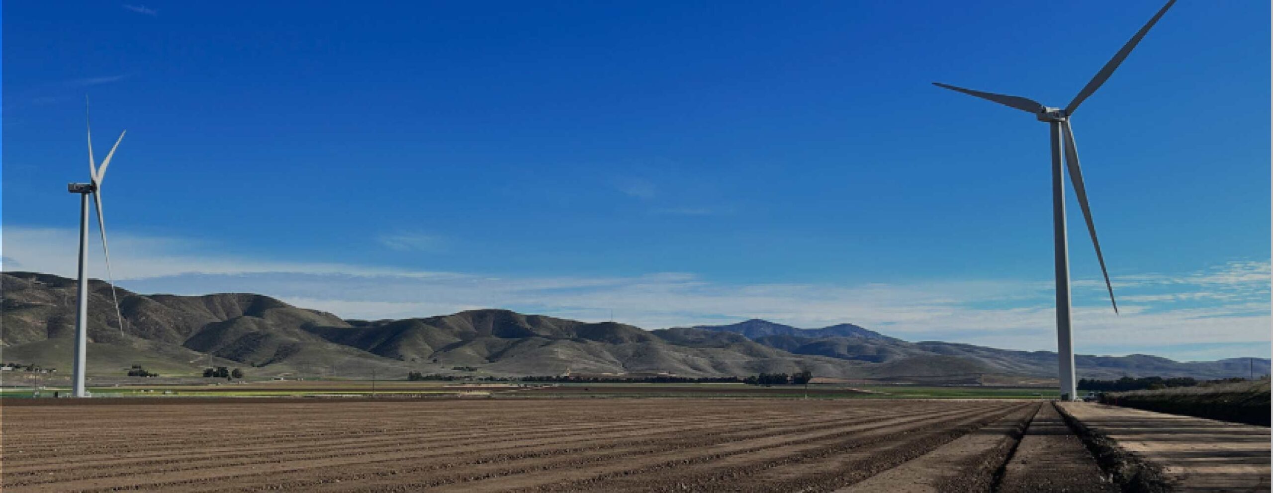 two wind power turbines on a land field