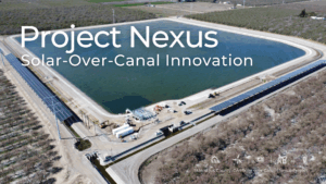 Aerial view of Project Nexus, a solar-over-canal installation in Stanislaus County, California. The image shows solar panel arrays mounted over irrigation canals surrounding a large water reservoir. Construction vehicles and equipment are visible on-site, highlighting the infrastructure work underway. The text overlay reads "Project Nexus: Solar-Over-Canal Innovation."